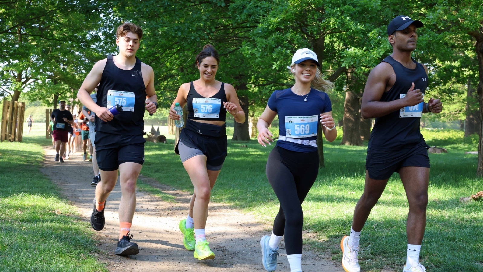 Quatre participants courant ensemble dans la bonne humeur sur les sentiers ombragés de Richmond Park.
