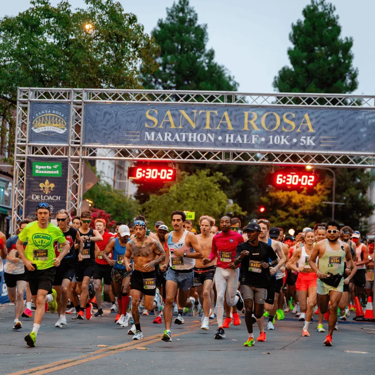 Départ du Santa Rosa Marathon avec un groupe de coureurs s'élançant sous l'arche officielle de la course.